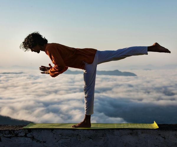 A silhouette of a man stretching against a sunrise.
